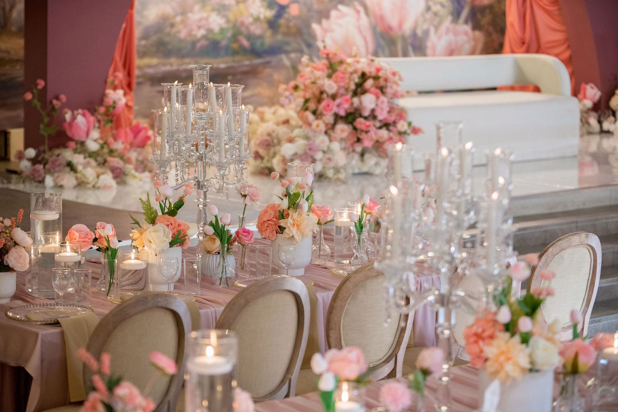 Pink flowers and glass candleholders along a long reception table