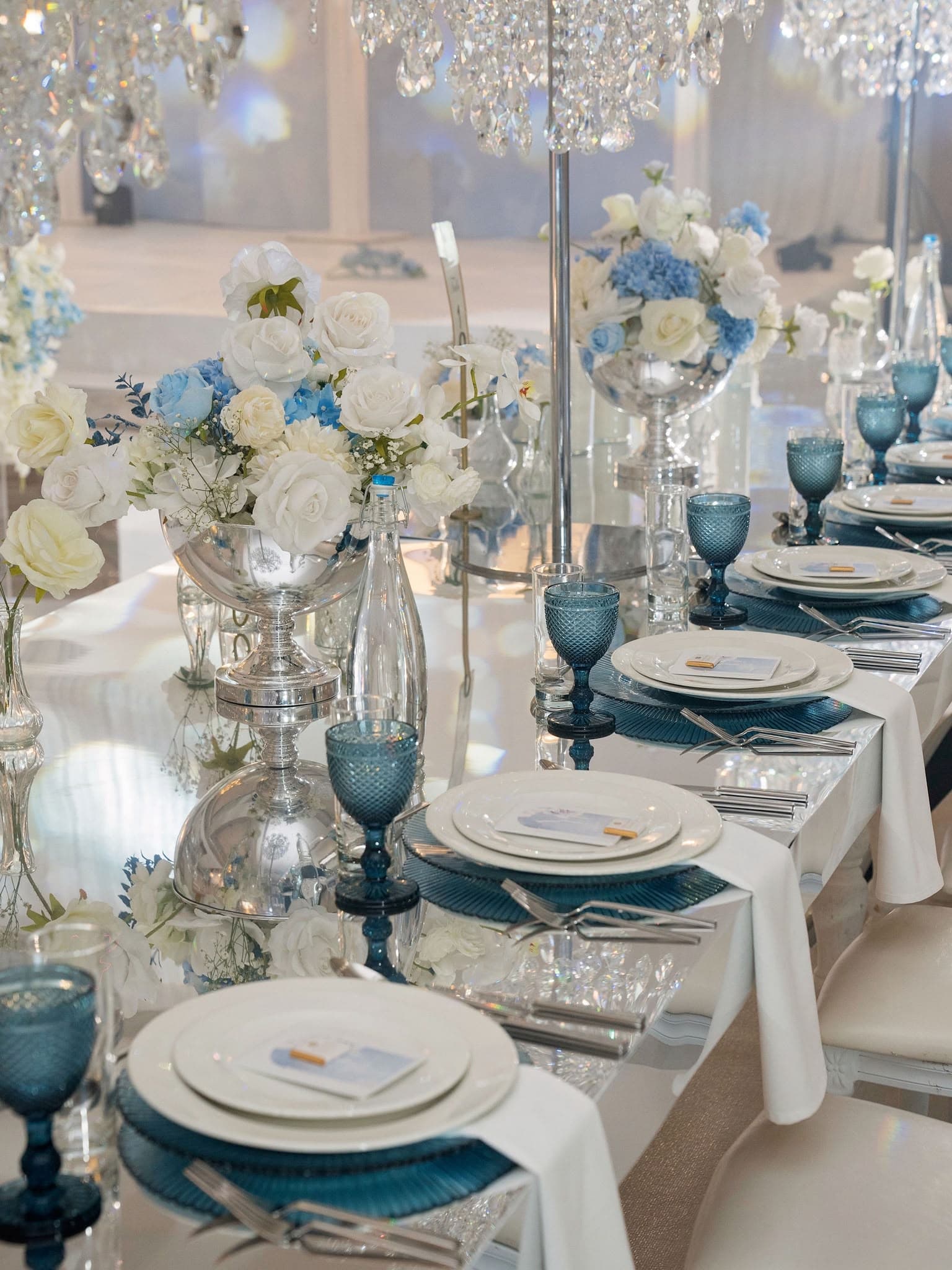 Blue glassware and floral details along a white reception table