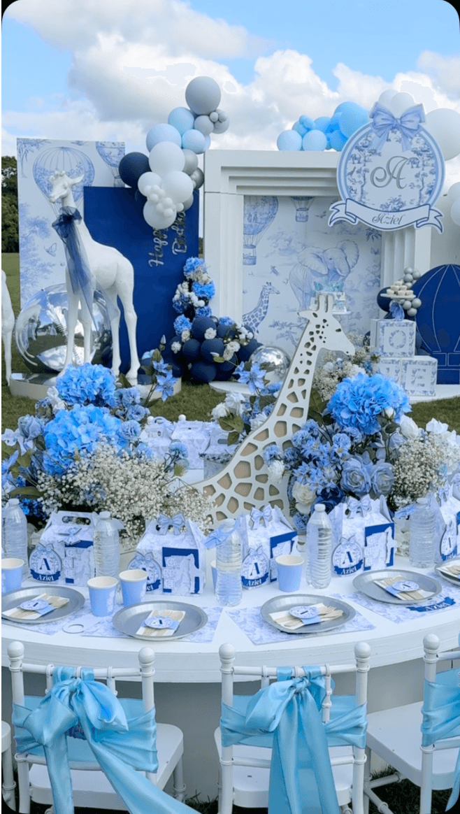 An outdoor children's celebration with blue flowers, balloons and safari decorations